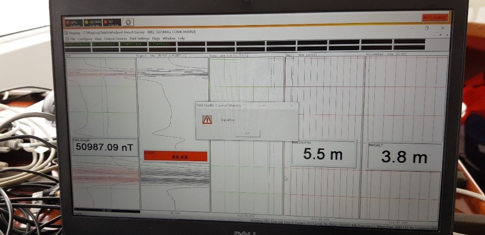 Samlerhuset: Bilde av skjerm som viser undersøkelser med magnetometer. Tall på skjermen viser dybde og utslag. 